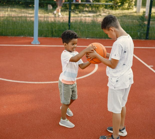 two-multiracional-brothers-playing-basketball-court-near-park